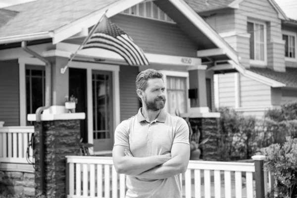 bearded man broker selling or renting house with american flag, home.