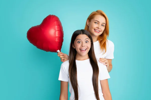 Love mom. Mother and daughter hold heart balloon. Happy mother and daughter holding love heart balloon on blue background