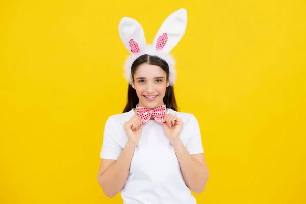 Beautiful girl with bunny ears isolated on yellow background. Easter bunny woman looks fun