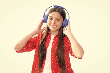 Teenager in modern wireless headphones enjoying song music in audio app, listening to her favorite music over white studio background. Happy teenager girl casual wear