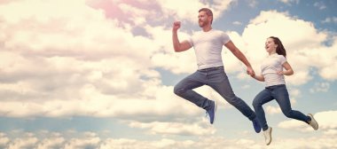 Baba ve kızı gökyüzüne sıçrıyor, fotokopi alanı olan bir pankart. Enerjik baba ve kız gökyüzüne atlıyorlar..