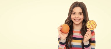 Portakal meyveli ve lolipoplu renkli kazaklı mutlu çocuk beyaz ve sağlıklı bir çocuklukta izole edilmiş. Portakallı, yatay posterli çocuk portresi. Kopyalama alanı olan başlık