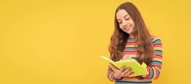 Mutlu kız çocuğu defterine sarı arka plan yazın. Öğrenci portresi, stüdyo afişi. Okul çocuğu yüzü, boşluklar