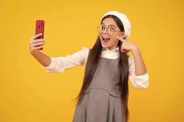 Kids selfie. Teenage girl with smart phone. Portrait of teen child using mobile phone, cell web app. Excited teenager girl