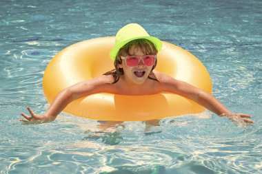 Child splashing in swimming pool. Active healthy lifestyle, swim water sport activity on summer vacation with child. Child in water play with inflatable toy ring