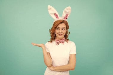 Mavi arka planda tavşan kulaklı mutlu Paskalya kadını. ürün sunuluyor.