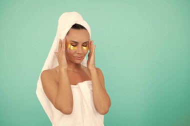 young woman in shower towel with golden patch. copy space.