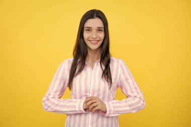 Pretty woman in shirt looking with satisfaction. Studio shot of beautiful woman isolated against yellow background