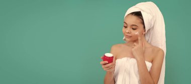 pretty kid in bath tower applying skin cream, healthy skin. Cosmetics and skin care for teenager child, poster design. Beauty kid girl banner with copy space