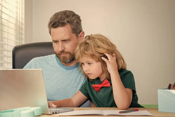bearded dad or school private tutor teaching boy son with modern laptop, webinar.