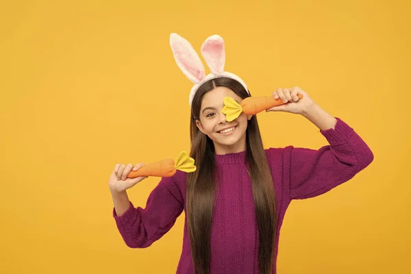 lets play. happy teen girl wear bunny ears hold carrot. happy easter. childhood happiness. child in rabbit costume. time for fun. adorable kid wearing funny hare ears. easter spring holiday.