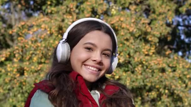 正处于青春期的女孩在耳机里听音乐 少女的慢动作在耳机里听音乐 戴耳机的少女听音乐 十几岁的女孩在无线耳机里听音乐 — 图库视频影像