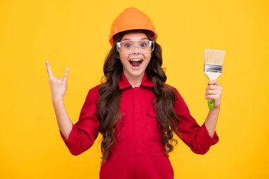 İnşaat alanında küçük miğfer ustası. Fırça aletli ya da boya silindirli genç kız ressam. Tamir işinde olan bir çocuk. Yenileme konsepti. Mutlu gülümseyen kız