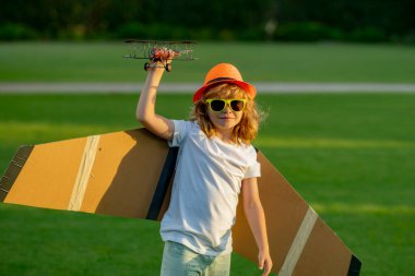 Child in the village with plane in his hands. Happy childhood. Summer portrait of happy cute child. Enjoying life and nature. Little child boy is playing and dreaming of flying. Childhood concept