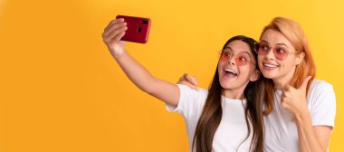 Mother and daughter child banner, copy space, isolated background. stylish mom and kid bloggers. happy woman and girl take selfie with smartphone. selfie family