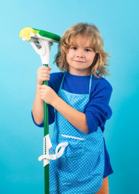 Child doing housework. Little kid cleaning at home. Child doing housework having fun. Studio isoalted portrait of child housekeeper with wet flat mop on blue background