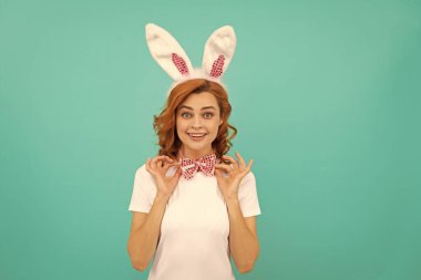 Tavşan kulaklı mutlu Paskalya kızı ve mavi arka planda papyon..