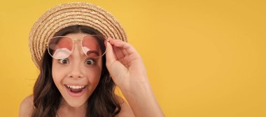 Yazlık hasır şapkalı ve gözlüklü çocuğun sarı arka planda kıvırcık saçları var, plaj modasında. Çocuk yüzü, yatay poster, izole edilmiş genç kız portresi, fotokopi alanı olan pankart
