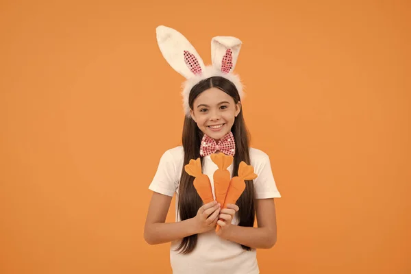 Ready to celebrate. time for fun. adorable kid looking funny with carrot. paschal spring holiday. happy teen girl wear bunny ears. happy easter. childhood happiness. child in rabbit ears and bow tie.