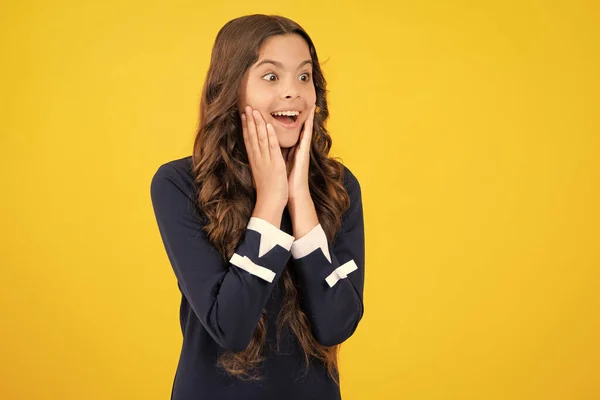 Excited face. Amazed expression, cheerful and glad. Teenager child girl with shocked facial expression. Surprised face expression, isolated on yellow background. Happy surprise