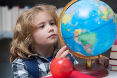 School kid looking at globe in library at the elementary school. Child from elementary school. Pupil go study. Clever schoolboy learning. Kids study, knowledge and education concept