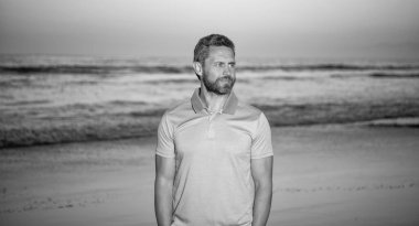 smiling bearded man over the sea on sunset summer beach, summer fashion.
