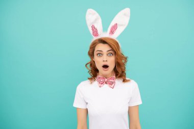 shocked easter woman with bunny ears on blue background.