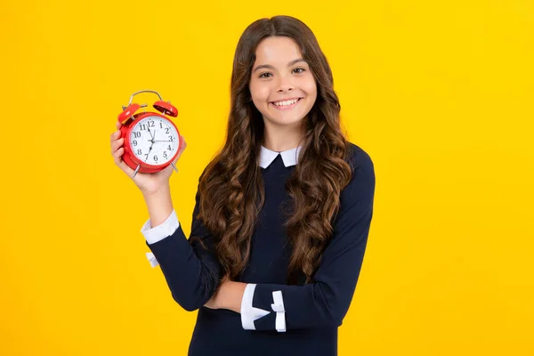黄色の背景に時計を持っているティーンの女の子 毎日のスケジュール 子供のチェック時間 遅刻するなよ 目覚まし時計の子供だ 締め切り — ストック写真