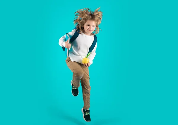 Back to school. Funny excited school concept. Little student boy with backpack go to study, jumping. Schoolchild, pupil jump on blue isolated background