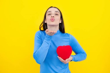 Genç bir kadın sevgililer günü konsepti, kalp şeklinde kartı olan bir kız. Sarı arka planda izole edilmiş sevgi sembolü el ele tutuşan sevimli bir kız.