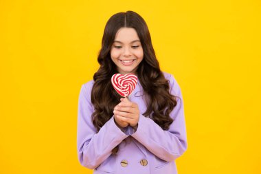 Sarı izole edilmiş arka planda lolipopu olan komik çocuk. Tatlı çocukluk hayatı. Lezzetli karamel lolipopu olan genç kız, şekerci. Mutlu ergen, pozitif ve gülümseyen genç kız duyguları