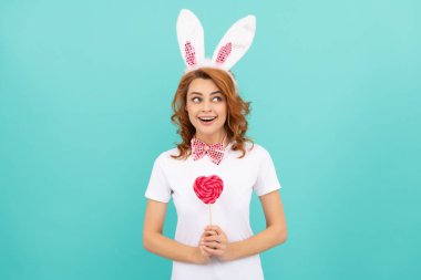 happy amazed easter woman wear bunny ears hold heart lollipop.