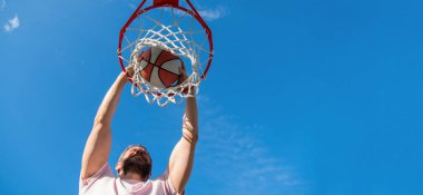 guy has sport motivation. sport and hobby. dunk in basket. slam dunk in motion. copy space. summer activity. man with basketball ball on court. professional basketball player training outdoor.
