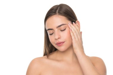 Kadın elleriyle yüzüne dokunuyor. Omuzları çıplak genç bir kız. Beyaz üzerinde izole edilmiş bir kadın portresi. Günlük alışkanlık ve kişisel bakım. Cilt güzelliği. pürüzsüz ve yumuşak kadın teni.