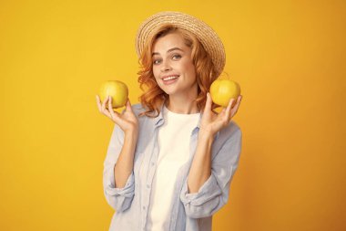 Elma tutan genç bir kadın. Seksi bir ifadeyle kameraya bakıyor. Neşeli ve mutlu bir yüz.