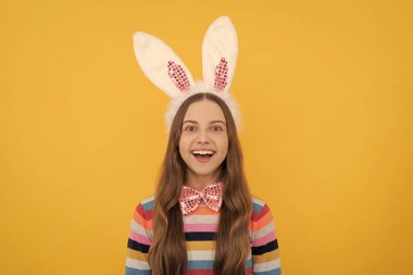 Tavşan kulaklı mutlu Paskalya çocuğu ve sarı arka planda papyon..
