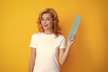 Güzellik saç bakımı. Saçlarını tarayan güzel bir kadın. Güzel görünümlü, çekici, bakımlı, neşe dolu tarağının portresi. Sarı arka planda saç efekti keratini izole edildi