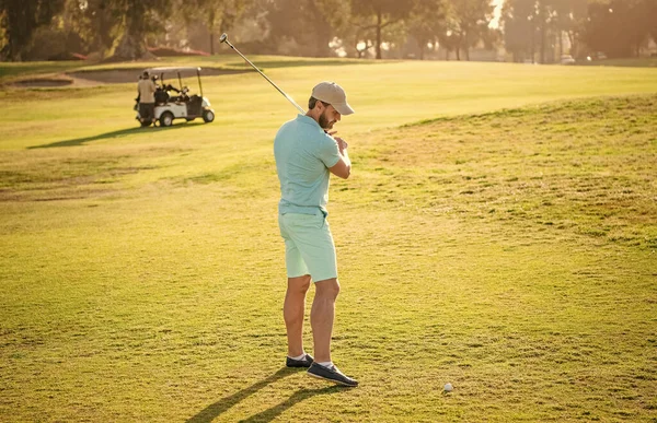 summer activity. professional sport outdoor. male golf player on professional golf course. portrait of golfer in cap with golf club. people lifestyle. athletic man playing game on green grass.