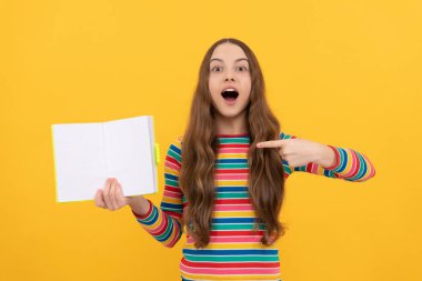 Bir göz at, bir kitap oku. Şaşırmış kız açık bir kitabı işaret ediyor. Edebiyat eğitimi. Edebiyat dersi. Okula dönelim. Başarılı olmak için oku, boşluğu kopyala.