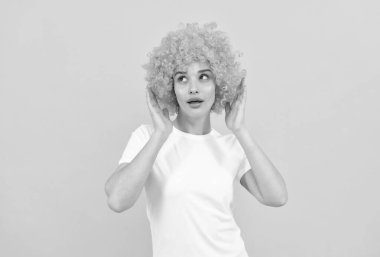 Şaşaalı parti bakışı. Sarı arka planda palyaço peruğu takan ucube kadın. Olumlu duygularını ifade et. Turuncu peruklu komik kız. 1 Nisan şakası. Mutlu bayan eğleniyor. Deliriyor.