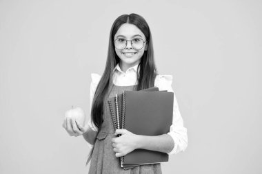 Okul çocuğu, çantalı genç kız. Elma ve kitap sarıda izole edilmiş.