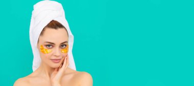 Eye patches, patch under eyes. young woman has collagen golden eye patches on face smile with towel. Beautiful woman isolated face portrait, banner with mock up copy space