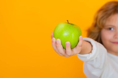 Stüdyoda elmalı çocuk. Stüdyo portresi sarı arka planda elma tutan şirin bir çocuk.