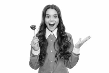 Şaşırmış çocuk portresinin uzun kıvırcık saçları var. Çikolatayı beyaz, leziz izmiş gibi tutuyor..