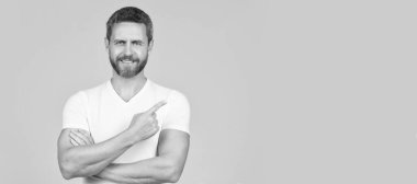 Gri arka plan fotokopi alanını işaret eden mutlu yakışıklı adam gülümsemesi, reklam. İnsan yüzü portresi, kopyalama alanı olan pankart