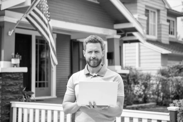 bearded man broker selling or renting house with american flag on pc online, home.