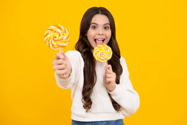 Cool teen child with lollipop over yellow isolated background. Sweet childhood life. Teen girl with yummy lollipop candy. Happy face, positive and smiling emotions of teenager girl