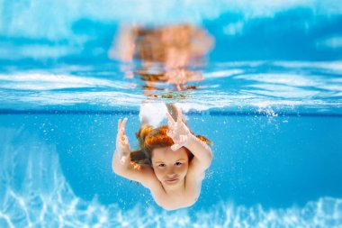 Kid swimming underwater on the beach on sea in summer. Blue ocean water. Child boy swimming in sea