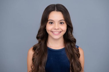 Mutlu kız yüzü, pozitif ve gülümseyen duygular. Güzel bir genç kızın yakın portresi. Sarı arka planda izole edilmiş Latin ya da İspanyol ergen çocuk