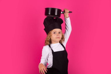 Kid chef cook with cooking pot. Cooking children. Chef kid boy making healthy food. Portrait of little child in chef hat isolated on studio background. Kid chef. Cooking process